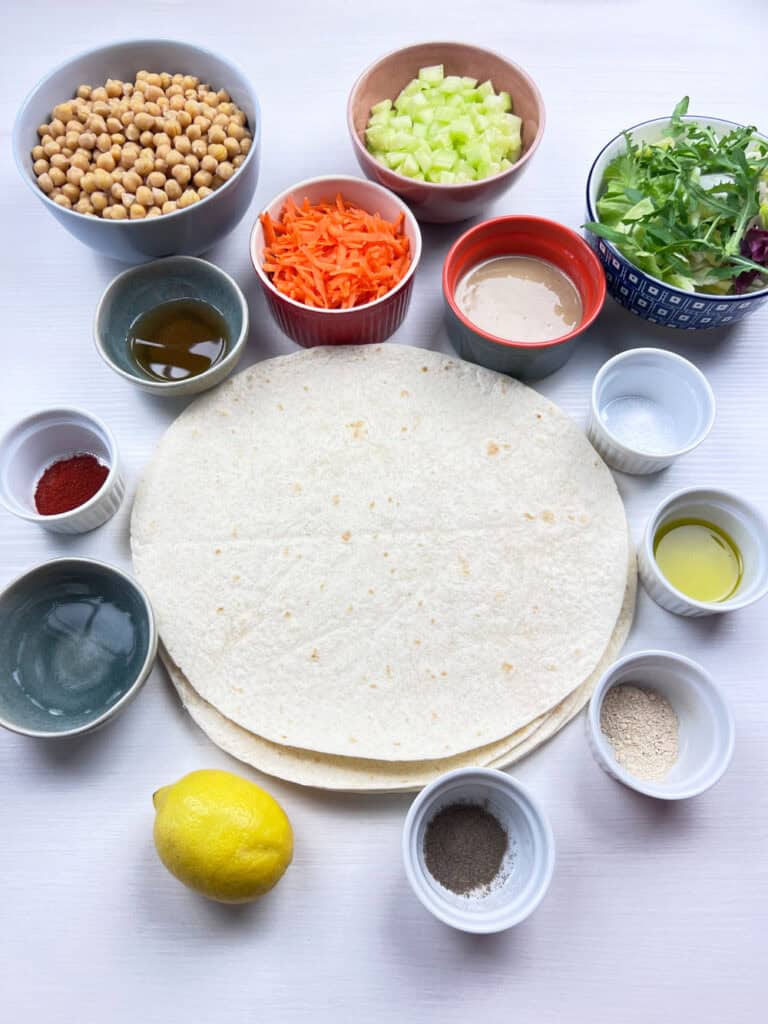 simple vegan ingredients for crispy chickpea salad wraps including tahini sauce, fresh veggies and tortillas