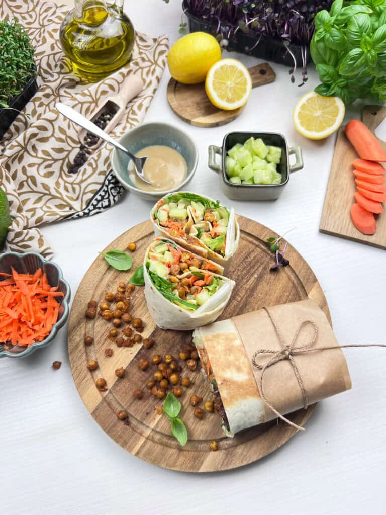 crispy chickpea salad wraps with tahini sauce, lettuce, carrots and cucumber on a serving board
