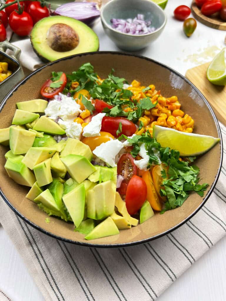 Close-up of vegan Mexican-style street corn bowls with fresh toppings over rice