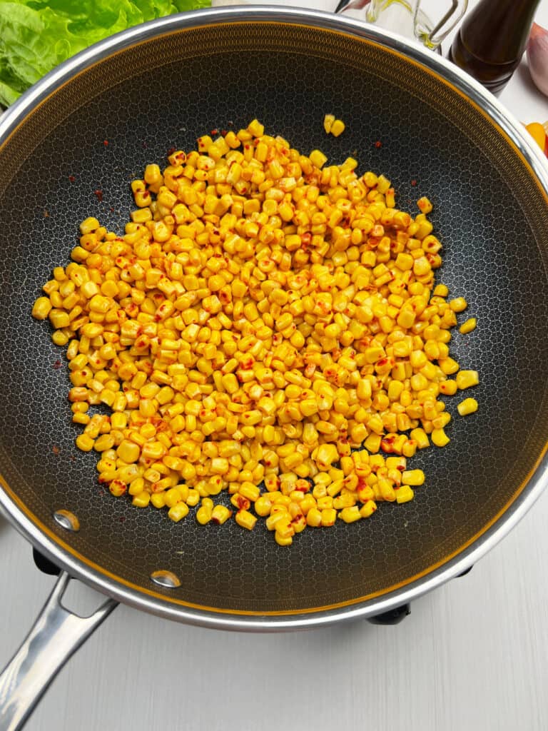 charring fresh corn in a skillet with spices for some dairy-free Mexican elote bowls