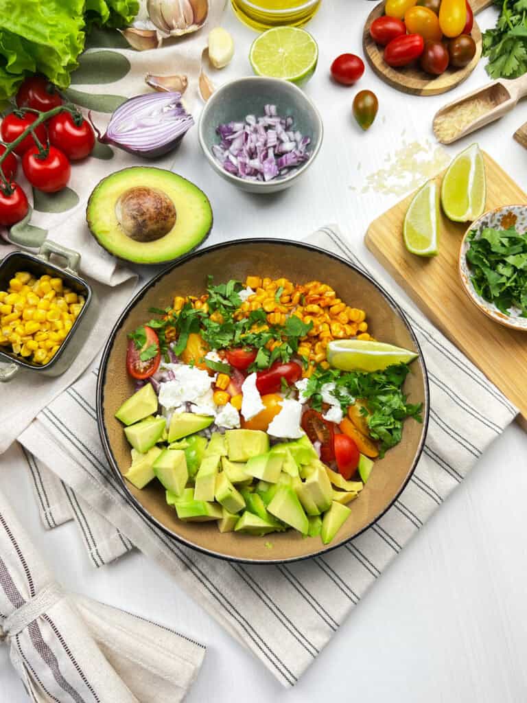 Overhead view of vegan elote bowl with rice and fresh veggie toppings
