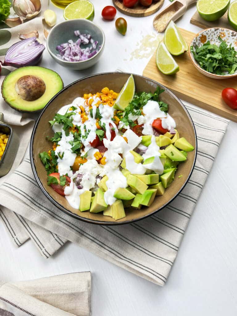 Vegan Mexican street corn bowl with avocado, cilantro, and creamy dairy-free elote sauce