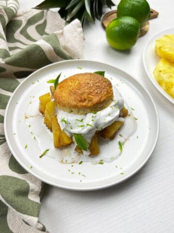 Angled view of flaky vegan shortcake layered with caramelized pineapple and coconut whipped cream