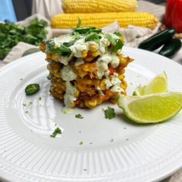 a clean stack of crispy vegan corn fritters topped with roasted jalapeno lime crema