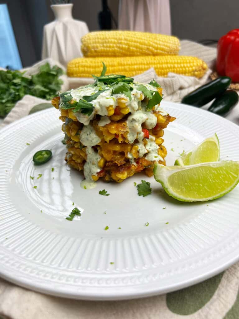 a clean stack of crispy vegan corn fritters topped with roasted jalapeno lime crema