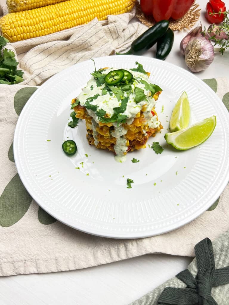Crispy sweet corn fritters stacked with creamy jalapeno lime crema and fresh garnish