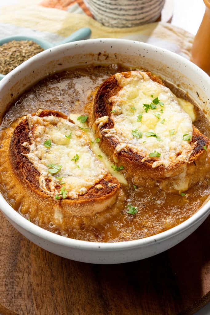 Hot bowl of French onion soup with caramelized onions and topped with dairy-free cheesy baguettes