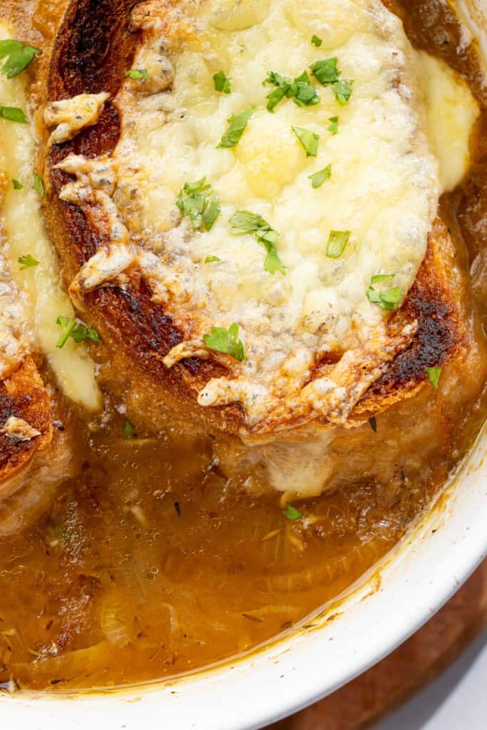 extreme closeup of vegan French onion soup with toasted baguette topped with cheese