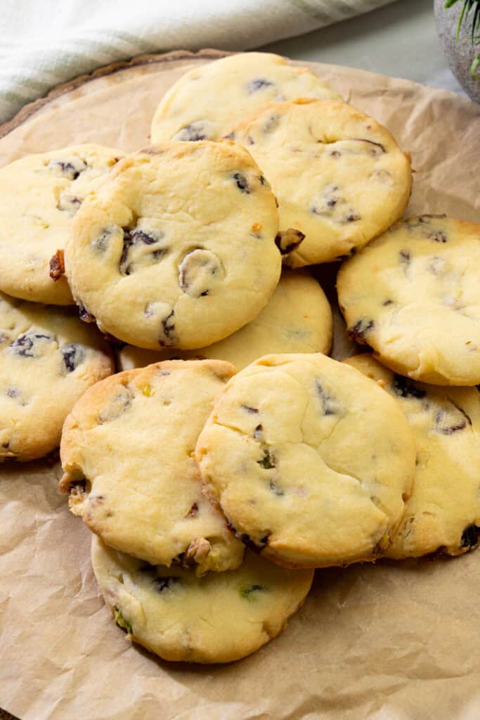 golden cranberry pistachio cookies arranged on parchment paper with soft centers and crispy edges