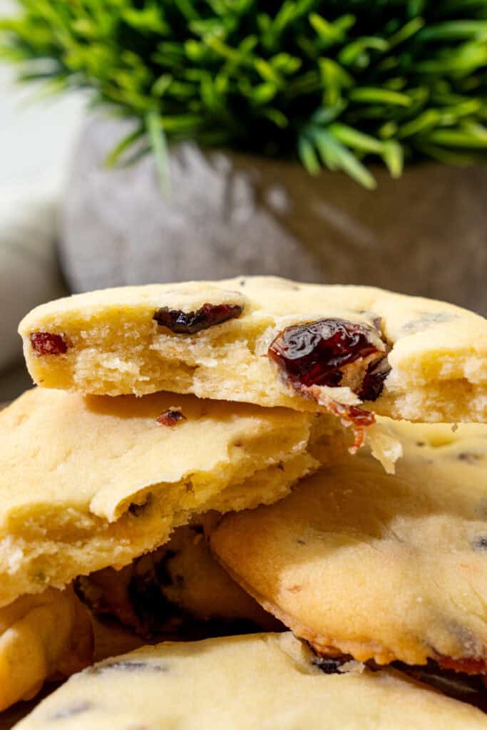 broken cranberry pistachio cookies stacked together revealing a tender, crumbly center