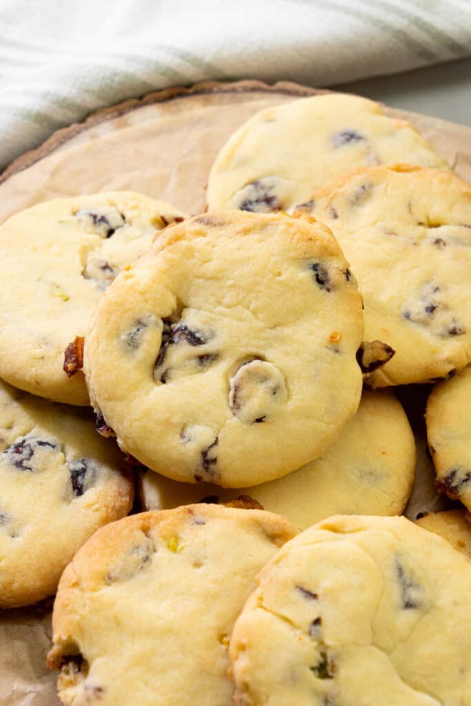 close-up of vegan cranberry pistachio shortbread cookies arranged together on a wood board