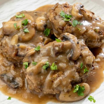 close up of vegan Salisbury steak covered in rich mushroom gravy topped with fresh parsley