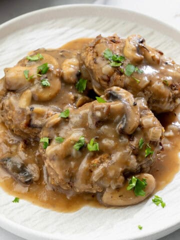 close up of vegan Salisbury steak covered in rich mushroom gravy topped with fresh parsley