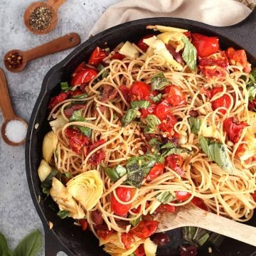 Finished pasta in a cast iron skillet with a wooden spoon