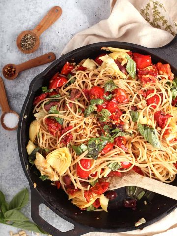 Finished pasta in a cast iron skillet with a wooden spoon