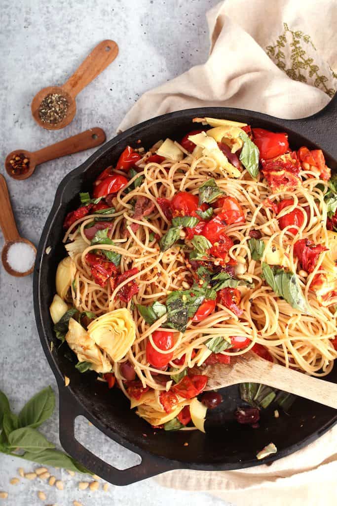 Finished pasta in a cast iron skillet with a wooden spoon