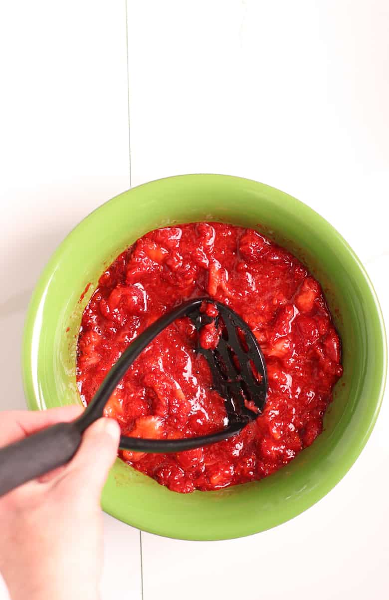 Crushed strawberries in a green bowl