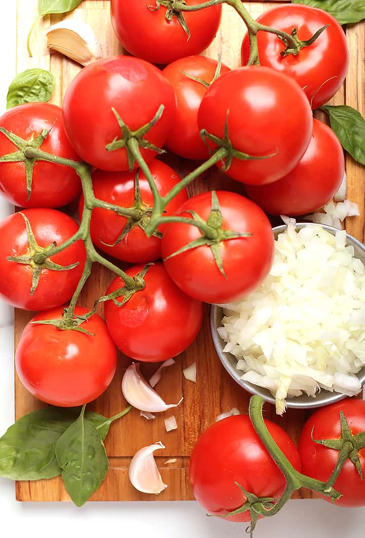 Fresh tomatoes, onions, and basil on cutting board