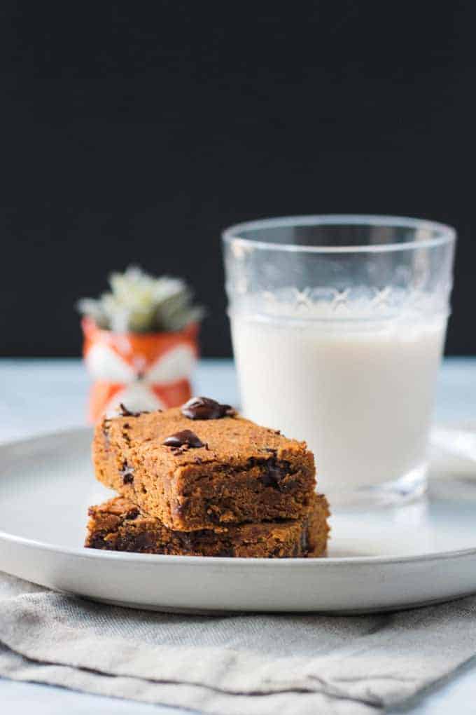 Chocolate Chip pumpkin bars on a white plate next to a glass of milk