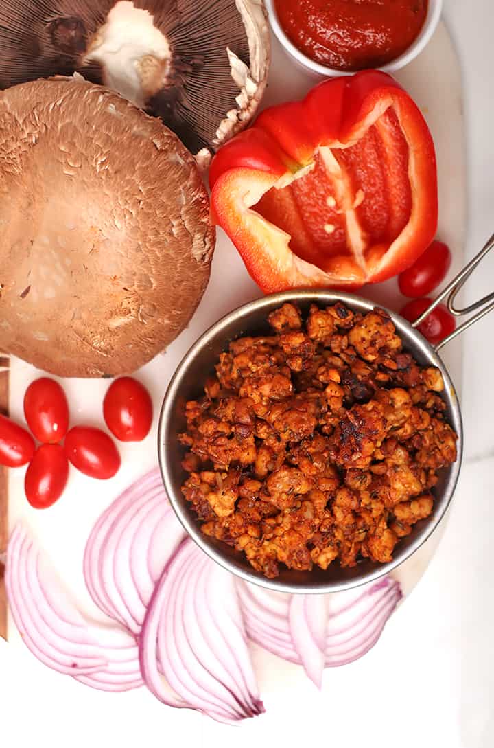 Tempeh sausage, onions, and tomatoes on cutting board