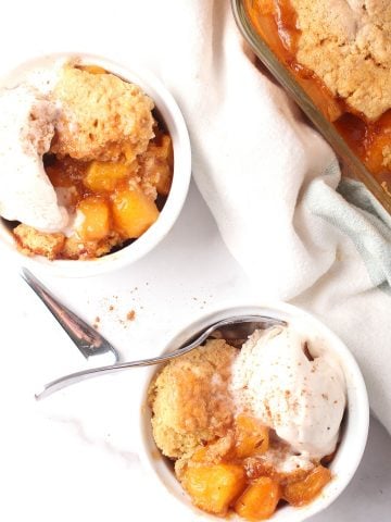 Two bowls of finished cobbler with vanilla ice cream