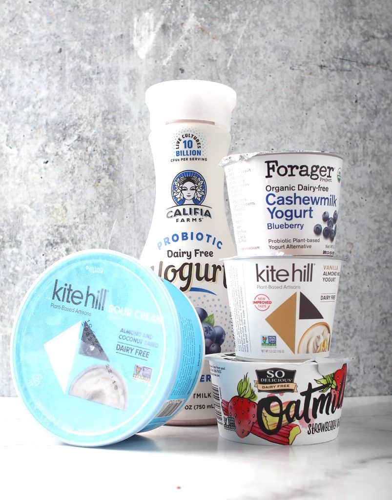 Vegan yogurt and cultured dairy stacked on a marble background